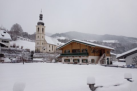 Hausansicht mit Kirche im Winter